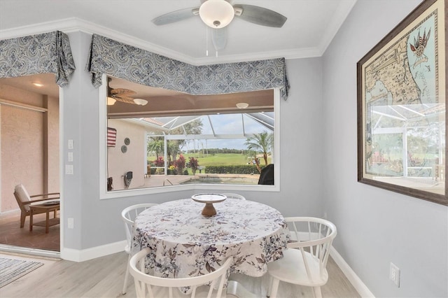 dining room featuring light wood-style flooring, ornamental molding, a sunroom, ceiling fan, and baseboards