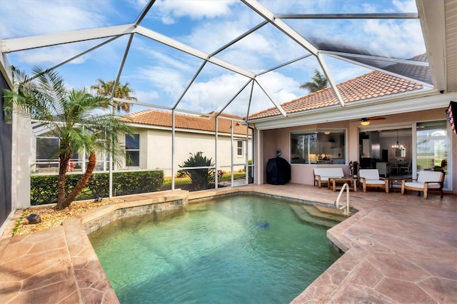 outdoor pool featuring glass enclosure, ceiling fan, and a patio area