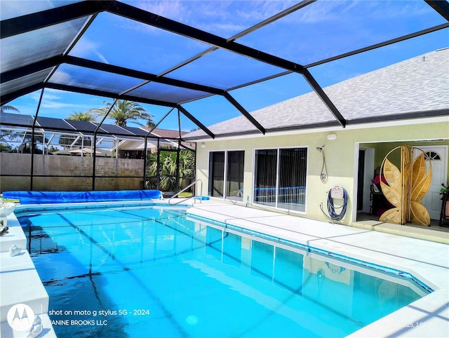 view of pool with glass enclosure, a covered pool, and a patio