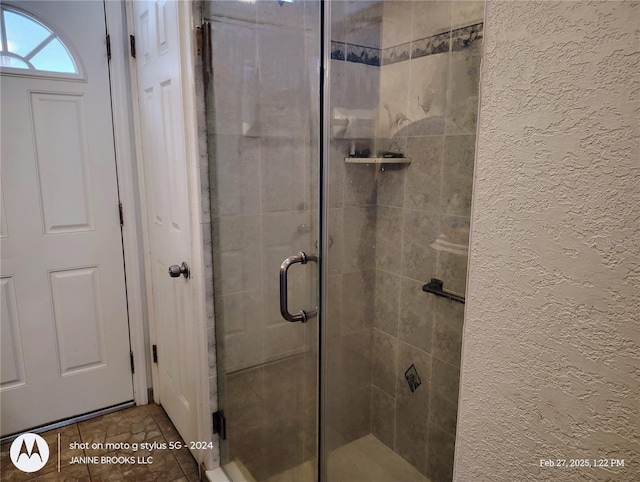 full bathroom with a stall shower, a textured wall, and tile patterned floors