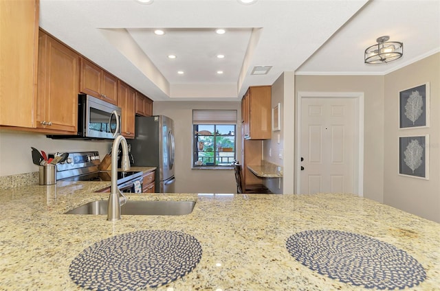 kitchen featuring stainless steel appliances, recessed lighting, brown cabinetry, a sink, and light stone countertops