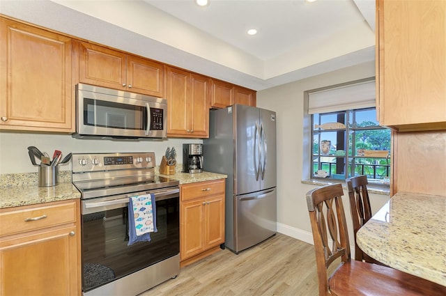 kitchen with baseboards, light stone counters, stainless steel appliances, light wood-type flooring, and recessed lighting