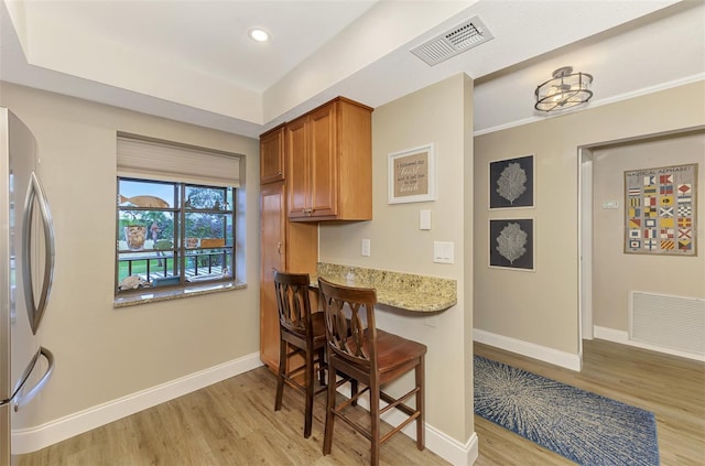 kitchen with freestanding refrigerator, visible vents, and baseboards