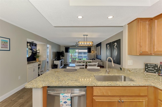 kitchen with a peninsula, a sink, open floor plan, stainless steel dishwasher, and light stone countertops