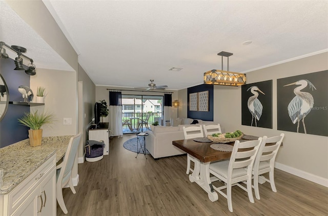 dining room featuring baseboards, dark wood finished floors, a ceiling fan, crown molding, and a textured ceiling