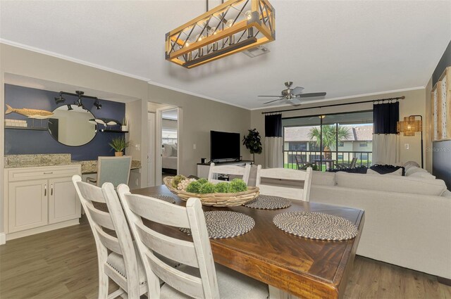 dining space featuring a ceiling fan, visible vents, ornamental molding, and dark wood-type flooring