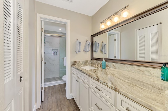 full bathroom featuring toilet, wood finished floors, vanity, a shower stall, and a closet