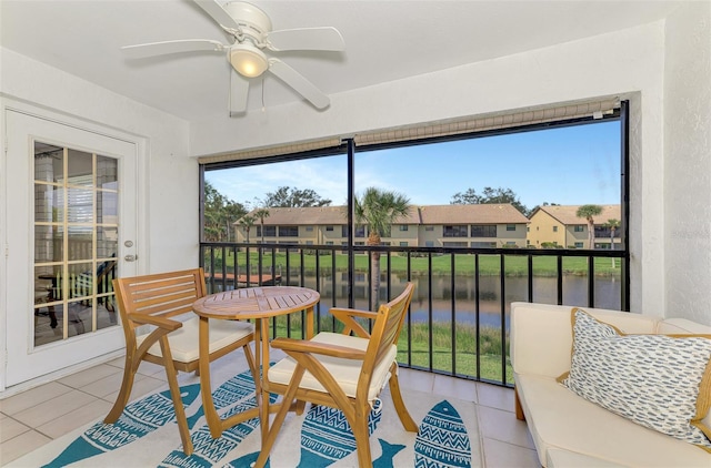 sunroom / solarium with a water view, a residential view, and a ceiling fan