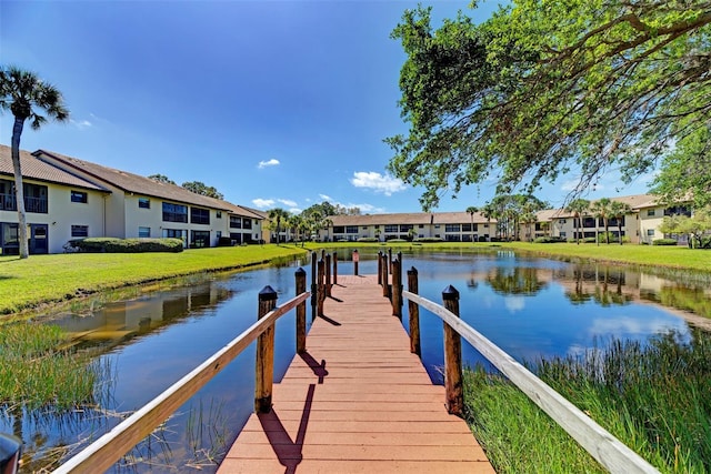 view of dock featuring a residential view, a water view, and a lawn