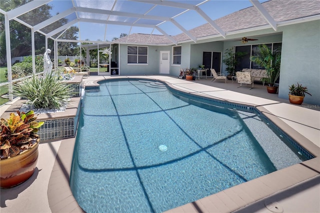 outdoor pool featuring a patio, glass enclosure, and a ceiling fan