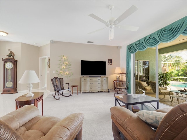 living area featuring light carpet, visible vents, and a ceiling fan