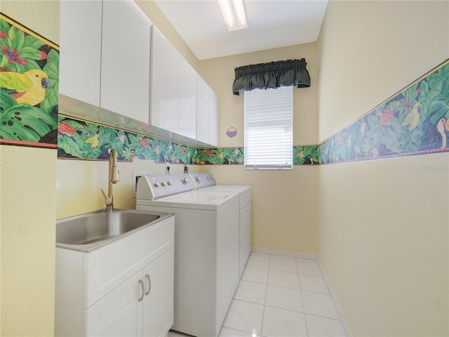 laundry area featuring cabinet space, light tile patterned floors, washer and clothes dryer, and a sink