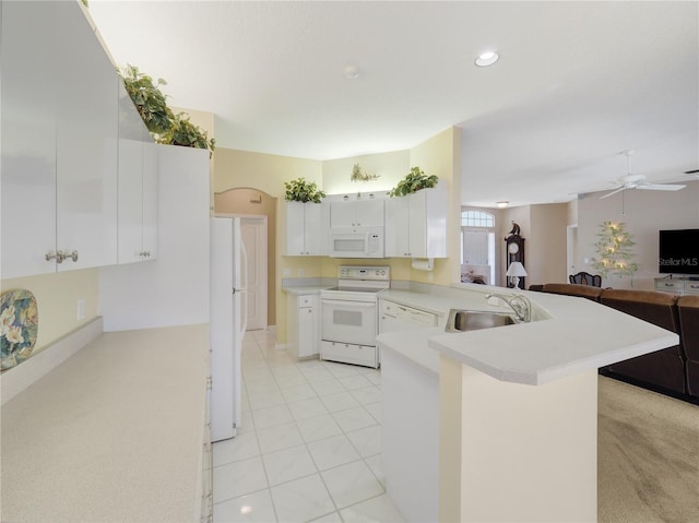 kitchen featuring a peninsula, white appliances, a sink, open floor plan, and light countertops