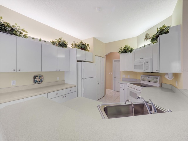 kitchen featuring arched walkways, white appliances, a sink, white cabinetry, and light countertops