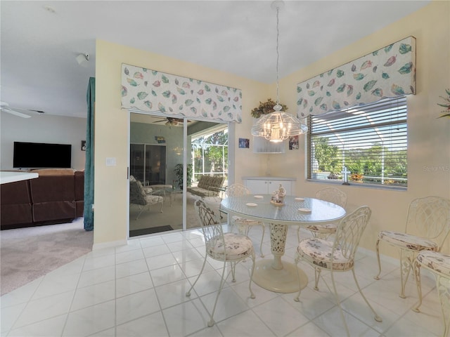 dining room with carpet floors, tile patterned floors, baseboards, and ceiling fan with notable chandelier