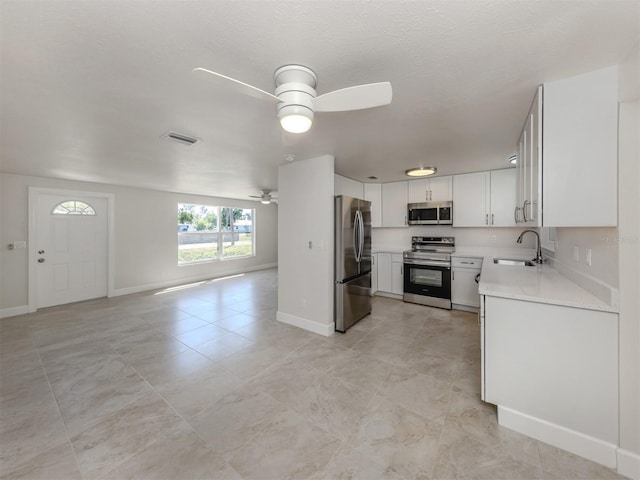 kitchen with a ceiling fan, a sink, light countertops, open floor plan, and stainless steel appliances
