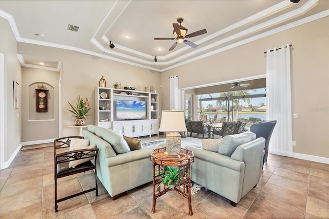 living room featuring ceiling fan, visible vents, baseboards, a tray ceiling, and crown molding