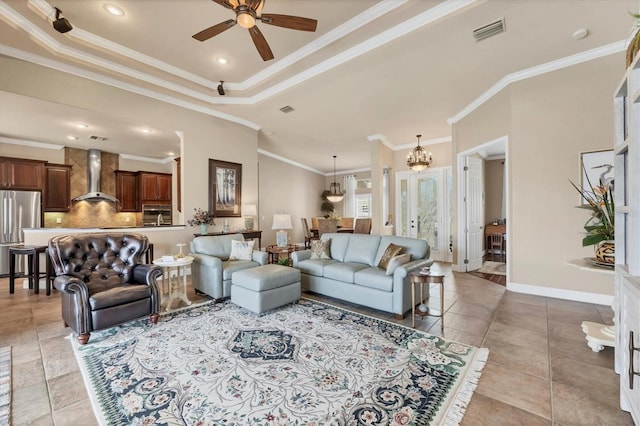 living room featuring a tray ceiling, crown molding, light tile patterned floors, visible vents, and baseboards