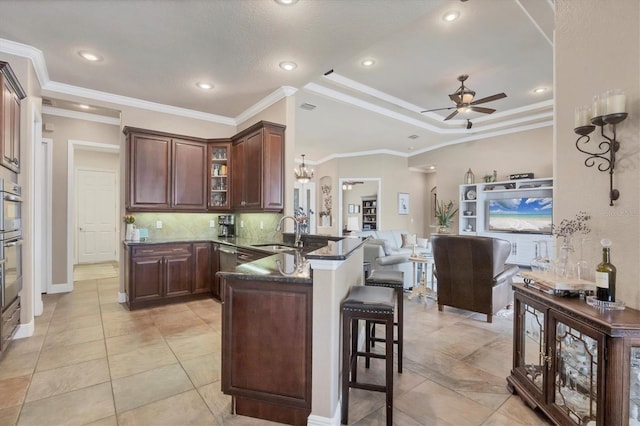 kitchen with glass insert cabinets, a breakfast bar, open floor plan, a peninsula, and a sink