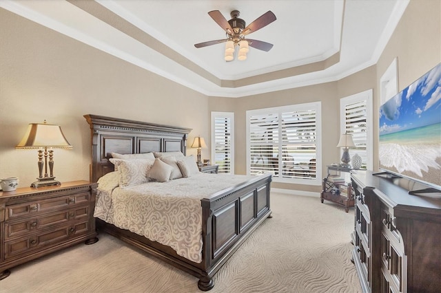 bedroom with a tray ceiling, crown molding, light carpet, ceiling fan, and baseboards