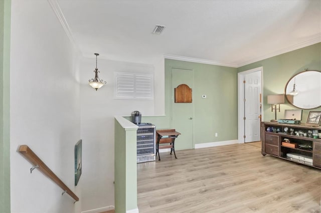 interior space featuring baseboards, light wood finished floors, visible vents, and crown molding