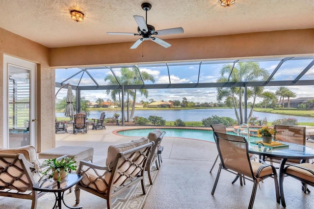 pool with a water view, a lanai, a ceiling fan, and a patio