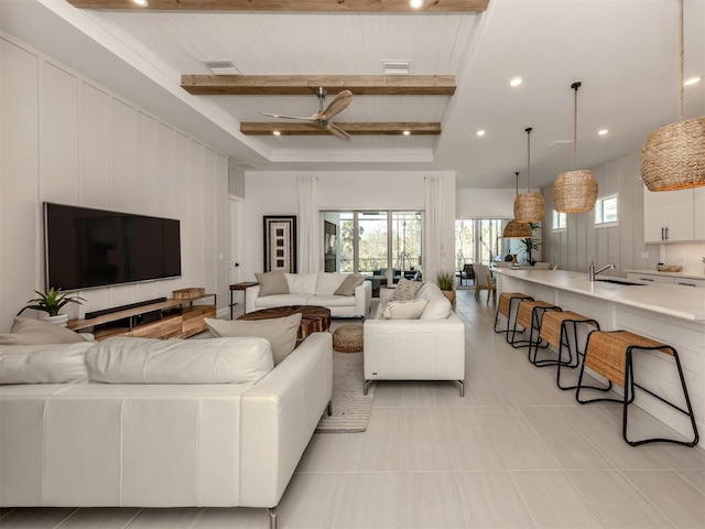 living area featuring visible vents, light tile patterned floors, beamed ceiling, and a ceiling fan