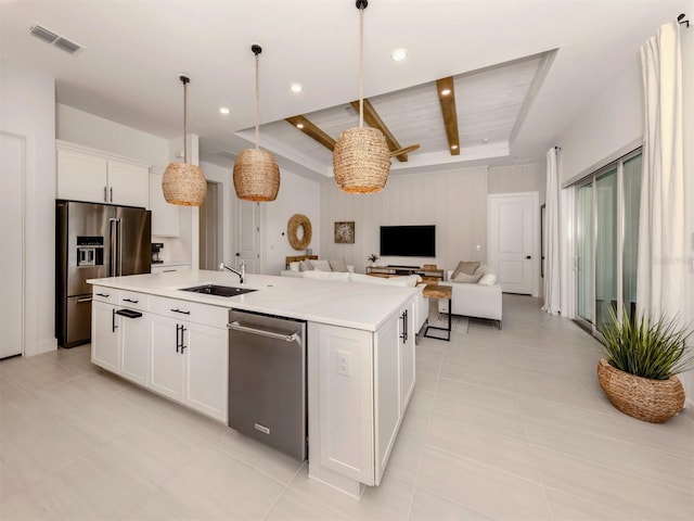 kitchen with an island with sink, appliances with stainless steel finishes, open floor plan, light countertops, and white cabinetry