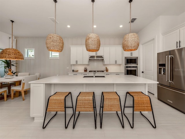 kitchen with a center island with sink, stainless steel appliances, and light countertops