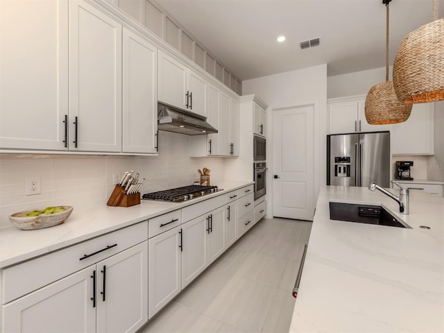 kitchen featuring under cabinet range hood, a sink, white cabinetry, appliances with stainless steel finishes, and decorative light fixtures