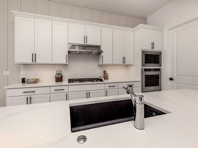 kitchen featuring stainless steel appliances, white cabinetry, and under cabinet range hood