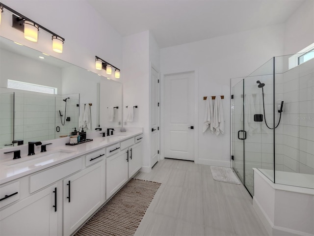 full bath featuring a sink, a shower stall, baseboards, and double vanity