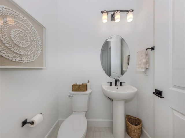 bathroom featuring a sink, toilet, and baseboards