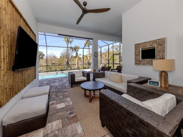 living room featuring a sunroom, ceiling fan, and stone tile floors