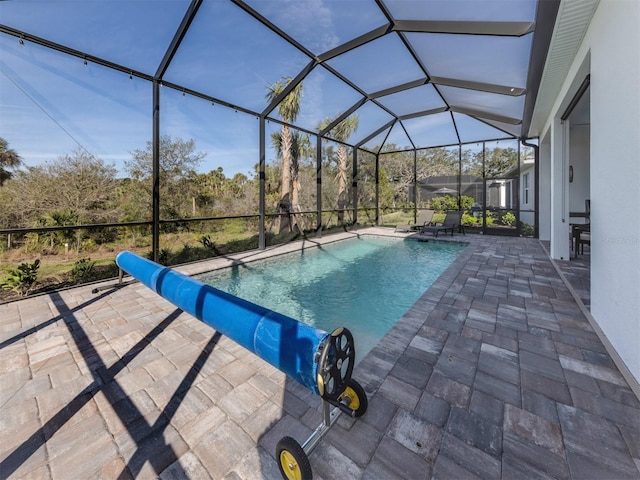 pool featuring a water slide, glass enclosure, and a patio