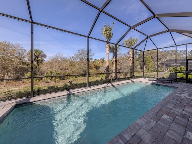 outdoor pool featuring glass enclosure and a patio