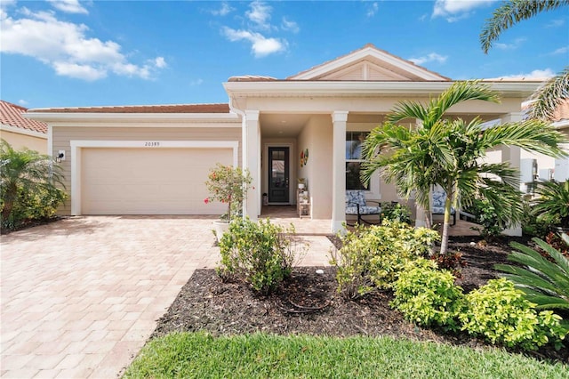 view of front of home featuring an attached garage, covered porch, and decorative driveway