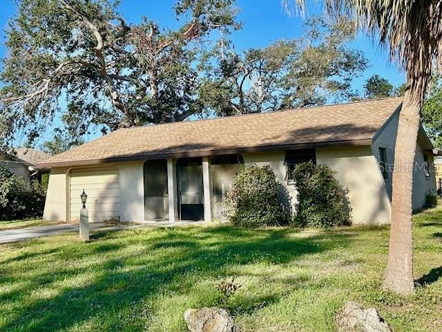 ranch-style home with driveway, a front lawn, an attached garage, and stucco siding