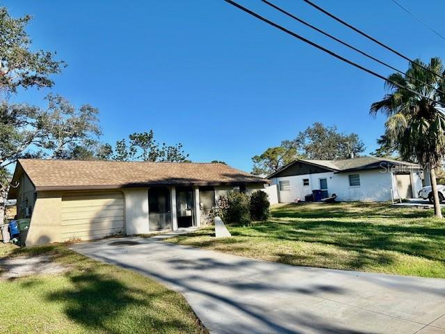 single story home featuring driveway, an attached garage, a front lawn, and stucco siding