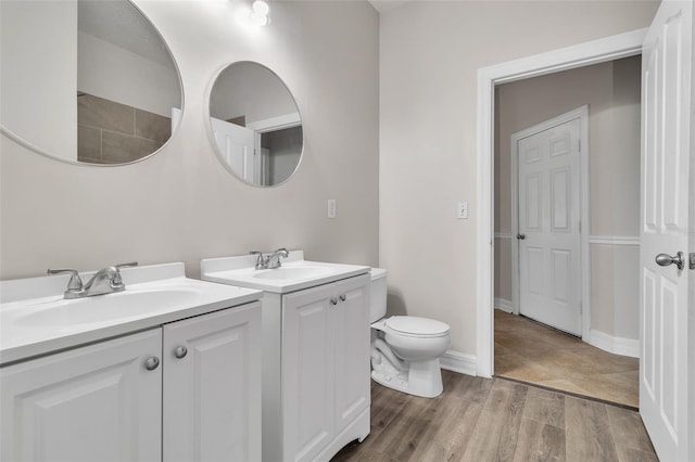 full bath with two vanities, a sink, baseboards, and wood finished floors