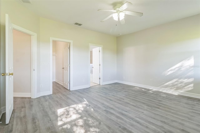 unfurnished bedroom featuring light wood-type flooring, baseboards, visible vents, and a walk in closet