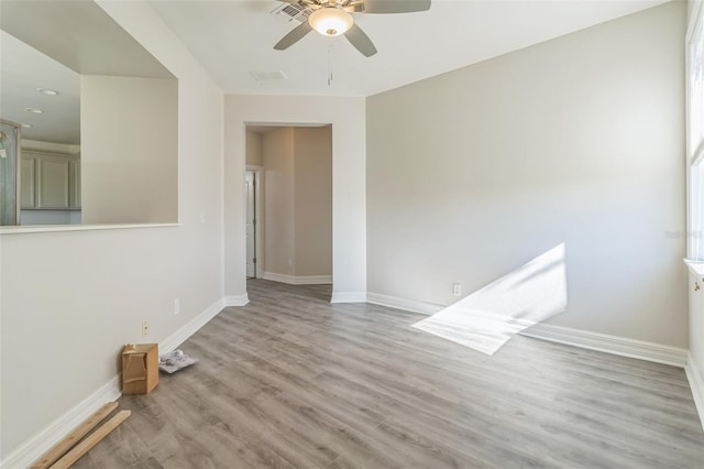 spare room with a ceiling fan, baseboards, visible vents, and light wood finished floors