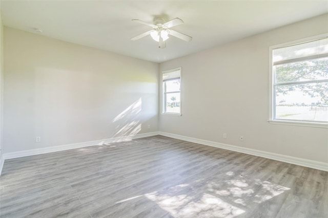 unfurnished room with a ceiling fan, light wood-type flooring, and baseboards