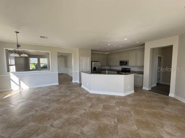 kitchen with pendant lighting, a center island with sink, stainless steel appliances, dark countertops, and open floor plan