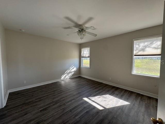 spare room with dark wood-style floors, ceiling fan, and baseboards