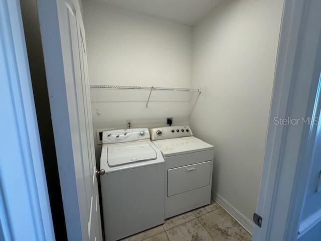 clothes washing area with laundry area, light tile patterned floors, baseboards, and separate washer and dryer