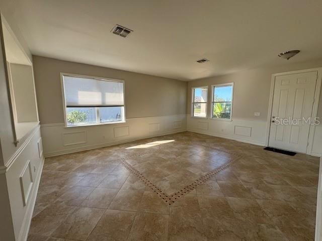 spare room with a wainscoted wall, visible vents, and a decorative wall