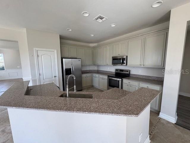 kitchen with light stone counters, recessed lighting, visible vents, appliances with stainless steel finishes, and a sink