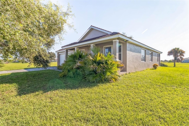 view of side of home with a garage, a lawn, and stucco siding