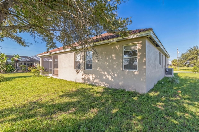 view of side of home with stucco siding, cooling unit, and a yard